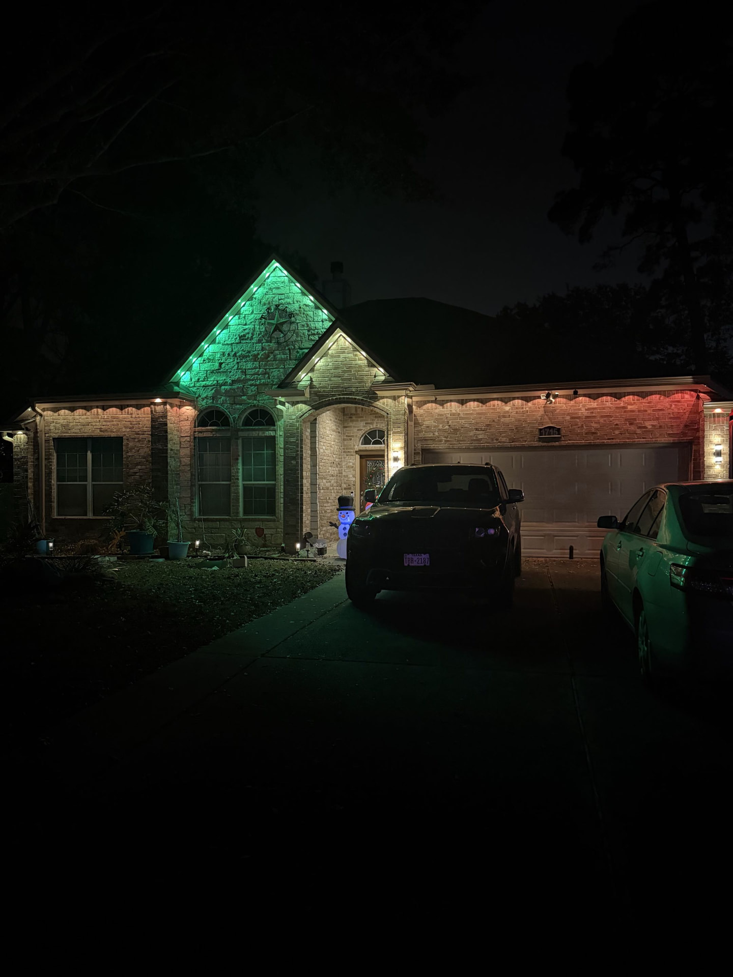 Festive red and green permanent LED holiday lighting on a Houston home